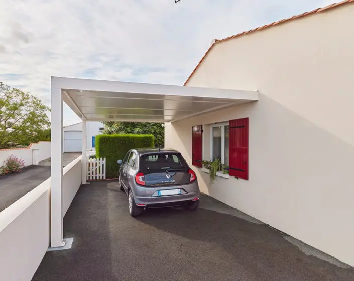 Carport blanc sur le côté de la maison, jonction avec le jardin